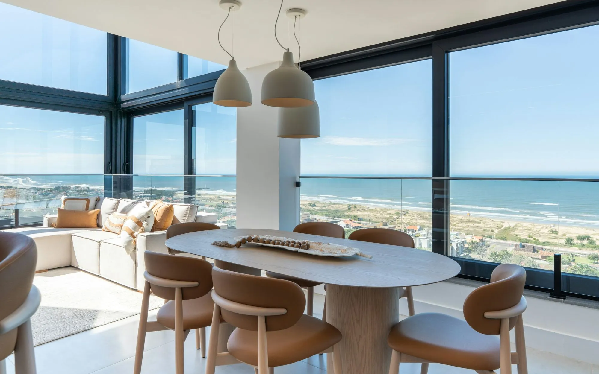 Sunlit dining area in a coastal home with clean floor to ceiling windows looking out to the ocean